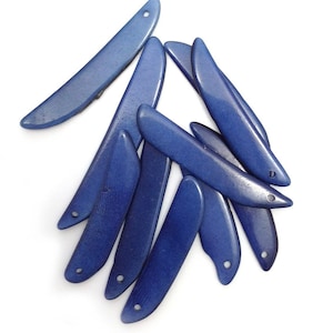 May include: A group of ten blue, ceramic, leaf-shaped beads with a hole at the top. The beads are arranged in a pile, with some overlapping.