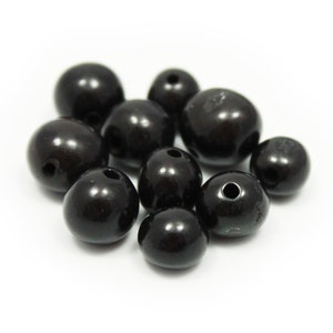 May include: A group of black round beads with a hole in the centre. The beads are smooth and shiny.