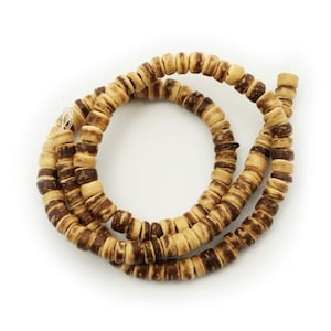 May include: A length of natural-toned wooden beads with dark brown markings. The beads are cylindrical and threaded together, forming a necklace or bracelet. The beads have a rustic, earthy look, ideal for jewellery making or craft projects.