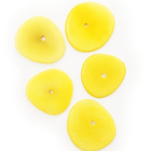 May include: Five yellow, irregularly shaped beads with a hole in the center. The beads have a smooth, glossy finish and are arranged on a white background. The beads are a bright, sunny yellow color.