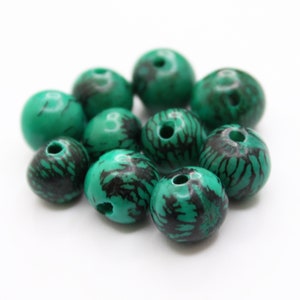 May include: A group of ten green and black wooden beads with a hole in the centre of each bead. The beads have a natural wood grain pattern and are perfect for jewellery making.