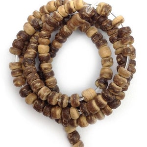 May include: A strand of natural-toned wooden beads. The beads are cylindrical and vary in shades of brown and tan. They are strung together on a thin, clear wire, creating a coiled pattern against a white background. The beads appear to be approximately 0.6 cm in diameter.