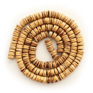 May include: A coiled strand of natural-toned wooden beads. The cylindrical beads have dark brown stripes, creating a textured pattern. The beads are strung together, forming a spiral shape against a white background.