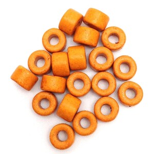 Könnte beinhalten: Eine Gruppe von 20 orangefarbenen Keramik-Donut-Perlen. Die Perlen haben einen Durchmesser von etwa 2,5 cm und ein Loch in der Mitte.