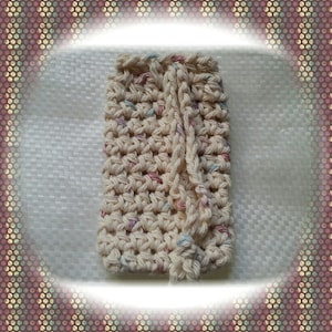 May include: A crocheted scrubby with a drawstring closure. The scrubby is made with a cream coloured yarn with pink, blue, and purple accents.