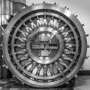 Puede incluir: Una gran puerta de b&oacute;veda redonda de metal con una serie de engranajes y palancas entrelazados. La puerta est&aacute; cerrada y tiene una peque&ntilde;a ventana circular en el centro.