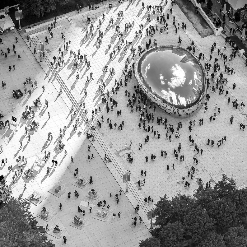 Puede incluir: Una vista a&eacute;rea de una gran escultura plateada reflectante en una plaza p&uacute;blica. La escultura est&aacute; rodeada de personas y el &aacute;rea circundante est&aacute; pavimentada con baldosas grises.