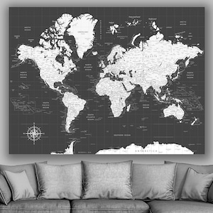 May include: A black and white world map print with a compass in the bottom left corner. The map is on a gray background and is framed.