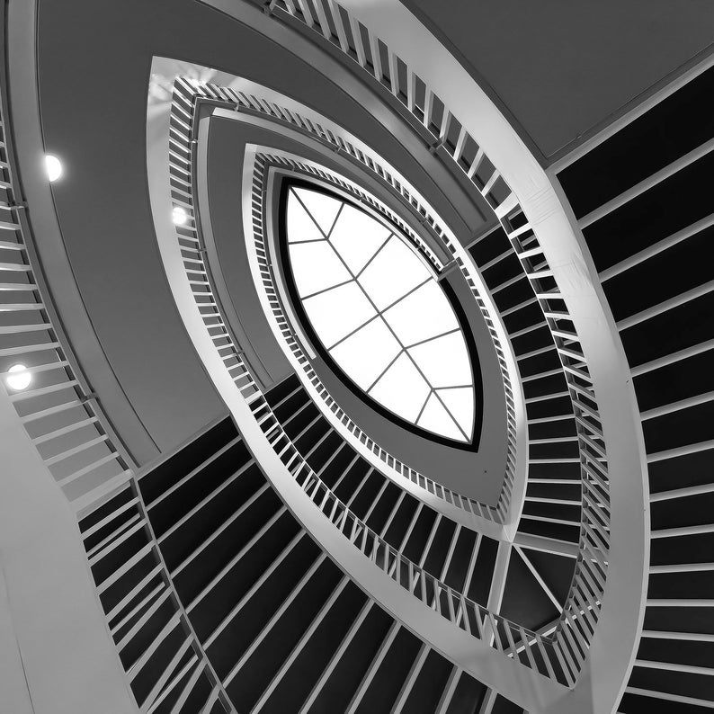 Puede incluir: Una fotograf&iacute;a en blanco y negro de una escalera de caracol con un gran tragaluz redondo en el centro. La escalera est&aacute; hecha de metal y tiene un dise&ntilde;o moderno.