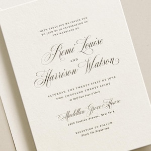 May include: Cream-coloured wedding invitation with stylish script. The invitation states "Remi Louise and Harrison Watson" with event details including the date, time, and location: Madellan Grove House, New York. An envelope accompanies the invitation.