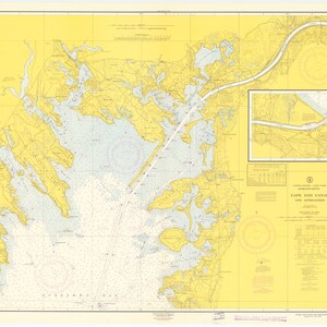 May include: A nautical chart of Cape Cod Canal and approaches, showing the waterway and surrounding land masses. The chart is printed on yellow paper with blue and black lines. The chart includes depth soundings, navigational aids, and other important information for mariners.