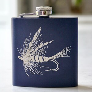 Op de afbeelding: Een donkerblauwe roestvrijstalen drinkfles met een zilveren dop en een wit silhouet van een vliegenvis-aasje.