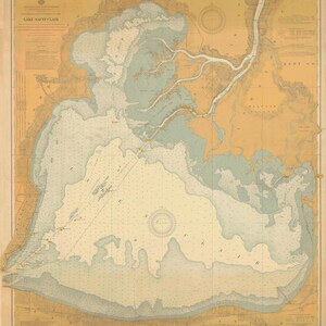 May include: A vintage map of Lake Saint Clair, a large body of water located on the border of Michigan and Ontario. The map is printed on a cream-colored paper with blue and brown lines indicating the waterways and land masses. The map includes a compass rose and a legend.