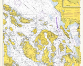 May include: A nautical chart of the Strait of Juan de Fuca and Strait of Georgia, showing the coastline and islands in yellow, with blue water and purple lines indicating channels. The chart includes depth soundings in fathoms.
