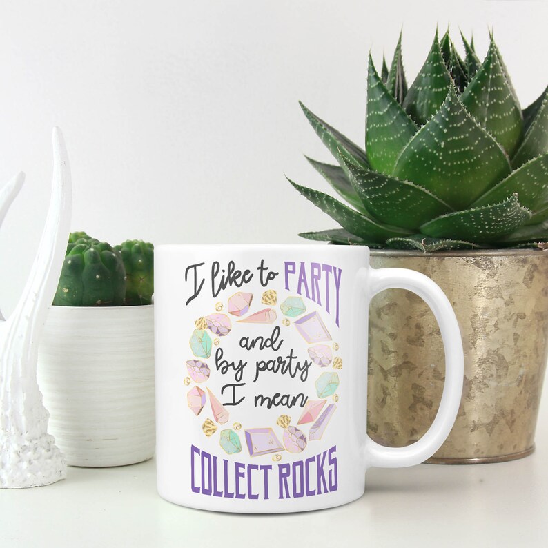 May include: White ceramic mug with a purple and gold design. The mug features the text "I like to party and by party I mean collect rocks".