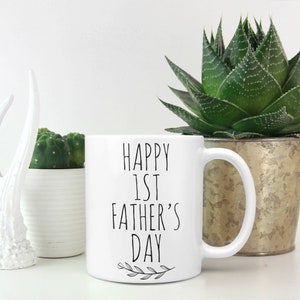 May include: White ceramic mug with black text that reads "Happy 1st Father's Day" with a small leaf design at the bottom.
