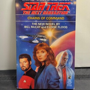 May include: A paperback book titled "Star Trek: The Next Generation: Chains of Command." The cover features images of characters and a spaceship against a starry background. The book is by Bill McCay and Eloise Flood.
