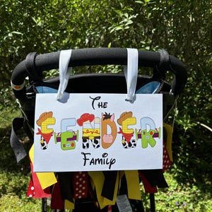 Op de afbeelding: Wit bord met de tekst "The Fender Family" in zwarte letters. De letters zijn versierd met afbeeldingen van personages uit de Toy Story-filmfranchise.