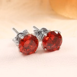 May include: A pair of silver stud earrings with red round gemstones.