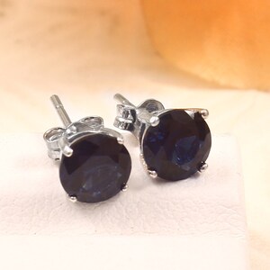 May include: A pair of silver stud earrings with dark blue round gemstones.