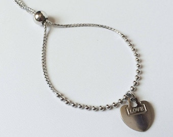Pode incluir: Um bracelete ajustável de prata com um fecho em forma de coração que diz "LOVE".