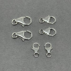 May include: Six silver lobster claw clasps in various sizes. The clasps are made of metal and have a shiny finish.