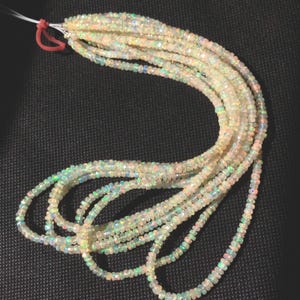 May include: Strands of iridescent opal beads, each with a unique play of color. The beads are small and faceted, strung together to create a flowing, textured appearance. The opals display flashes of green, blue, and yellow.