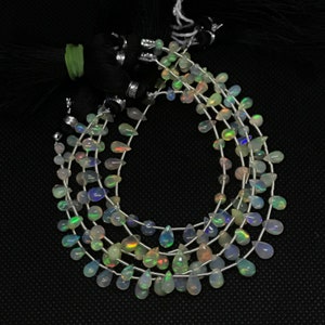May include: A strand of iridescent opal teardrop beads, strung on silver wire. The beads are a mix of white, green, and blue.