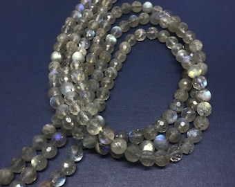 May include: A strand of iridescent grey labradorite gemstone beads. The beads are round and faceted, with a smooth, polished finish.