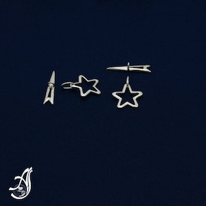 May include: Four silver metal star-shaped clasps for clothing. Two of the clasps are simple stars, and two are star-shaped with a small pin attached to the top.