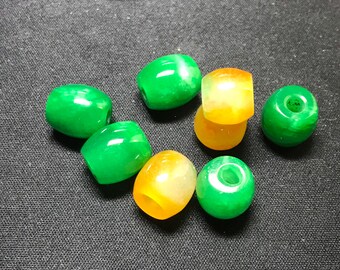 May include: A collection of seven jade beads, some green and some yellow, with a hole through the center of each bead.