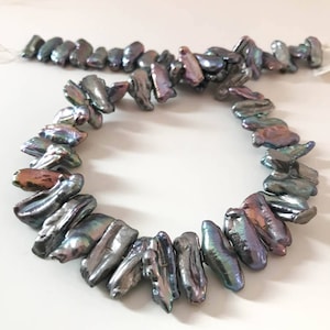 Puede incluir: Una hebra de perlas de agua dulce negras iridiscentes, cada perla tiene una forma irregular única. Las perlas están enhebradas en un hilo fino y están listas para ser utilizadas en la elaboración de joyas.