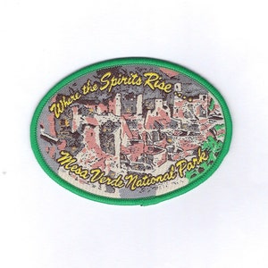 May include: A green and white embroidered patch featuring a picture of Mesa Verde National Park. The text on the patch reads "Where the Spirits Rise... Mesa Verde National Park".