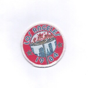 May include: A red, white, and blue embroidered patch with the text "Los Angeles 1984" and a depiction of the Olympic flame and cityscape.