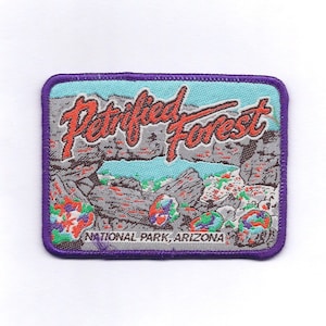 May include: Purple embroidered patch with a blue background featuring the text "Petrified Forest National Park, Arizona". The patch depicts a rocky landscape with a blue sky.