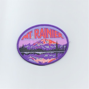 May include: Purple round patch featuring a mountain scene with the text "MT. RAINIER WASHINGTON" in white.