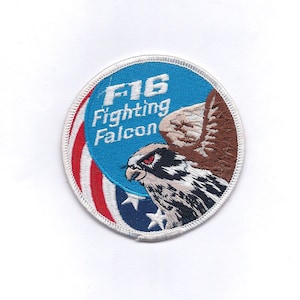 May include: An embroidered patch featuring a falcon and the text "F16 Fighting Falcon" in white, blue and red.