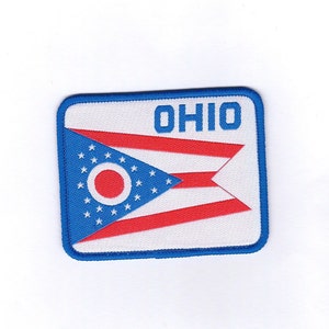 May include: A blue and red embroidered patch with the state flag of Ohio and the word "OHIO" in white lettering.