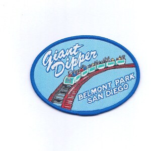 May include: A blue and white oval patch with the text "Giant Dipper" in white cursive lettering. The patch features a red and white roller coaster with people riding it. The text "Belmont Park San Diego" is printed in black below the roller coaster.
