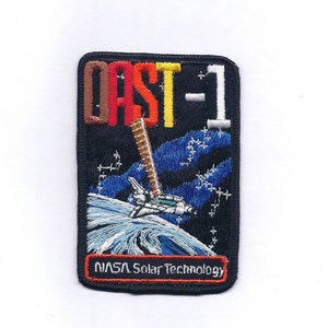 May include: A black embroidered patch with a white space shuttle in orbit around a blue and white Earth. The text "CAST-1" is in red, orange, yellow, and brown letters. The text "NASA Solar Technology" is in white letters on a red background.
