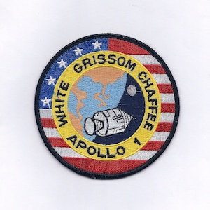 Peut inclure: Un écusson brodé circulaire avec un motif de drapeau américain rouge, blanc et bleu. L'écusson présente un cercle jaune avec le texte "WHITE GRISSOM CHAFFEE APOLLO 1" et une illustration blanche et grise d'un vaisseau spatial.