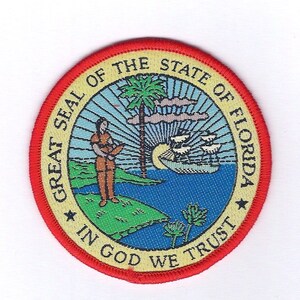 May include: A yellow and red embroidered patch with the Great Seal of the State of Florida. The seal features a sun rising over a body of water with a ship sailing on it. A palm tree stands in the center of the image. A man in a brown tunic stands on a green island to the left of the palm tree. The text "Great Seal of the State of Florida" is written in a circle around the image. The text "In God We Trust" is written in a semi-circle at the bottom of the image.