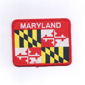 May include: An embroidered patch featuring the Maryland state flag in red, white and yellow, with the word "MARYLAND" in white lettering.