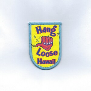 May include: A blue and yellow embroidered patch with the text "Hang Loose Hawaii" and a red hand giving a thumbs-up gesture.