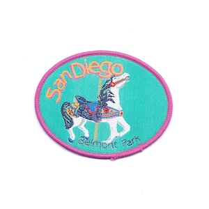 May include: A pink and green embroidered patch with the text "San Diego Belmont Park" and a white carousel horse with a colorful saddle.