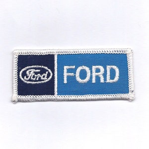 May include: A white embroidered patch with a blue background and the word "FORD" in white lettering. The left side of the patch is navy blue with a white oval containing the word "Ford" in white lettering.