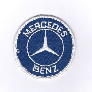 May include: A white embroidered patch with a blue circle containing a white three-pointed star and the text "Mercedes Benz".