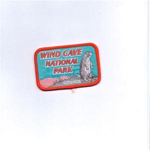 May include: A red, white, and blue embroidered patch with the text "Wind Cave National Park" and a prairie dog illustration. The text "Prairie Dog" is printed below the illustration.