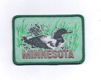 May include: A green embroidered patch with a loon on a green background and the word "MINNESOTA" in brown lettering.