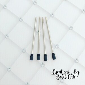 May include: Four silver pen refills with black rubber tips. The refills are arranged vertically on a white background.